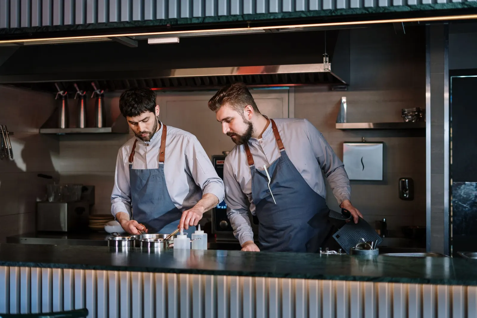 Two cooks working in an open restaurant kitchen